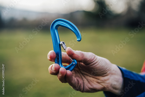 Close up shot of a climbing carabiner in climber's hand. Colorful biner for climbing and mountaineering. Detail shot of climbing equipment. photo