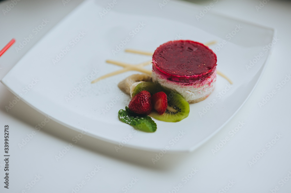 Tasty ice cream pudding with cherry jam, garnished with strawberries and kiwi on a plate close-up. Fresh dessert. Photography, concept. Tasty ice cream pudding with cherry jam, garnished with strawberries and kiwi on a plate close-up. Fresh dessert. Photography, concept.