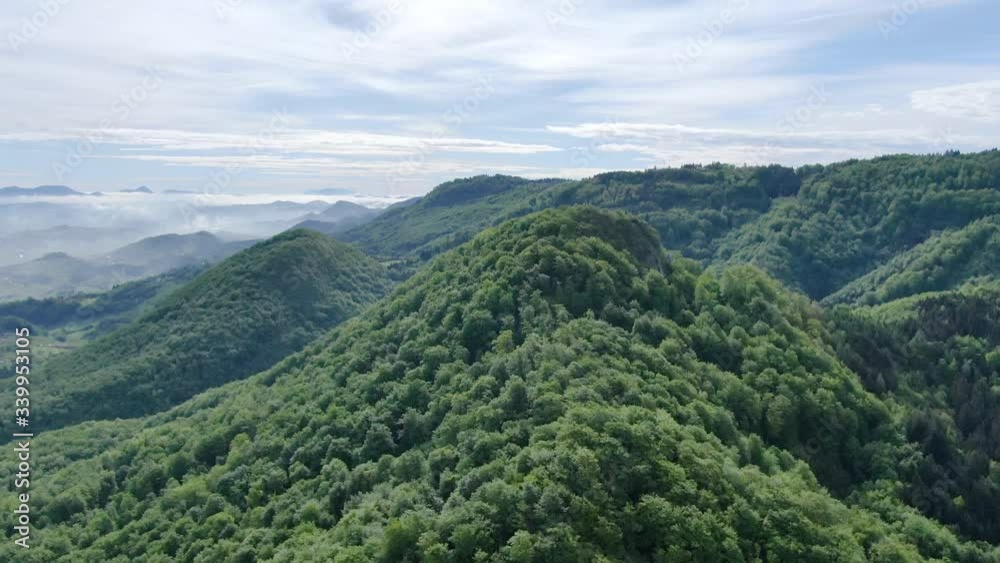 Green mountain range completely covered with trees with clouds hanging low between the hills. Lush green hills completely covered by forest. Aerial shot. Green mountain range completely covered with trees with clouds hanging low between the hills. Lush green hills completely covered by forest. Aerial shot.