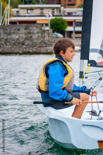 child sails on a sailing boat, course for beginners in the summer on the lake
