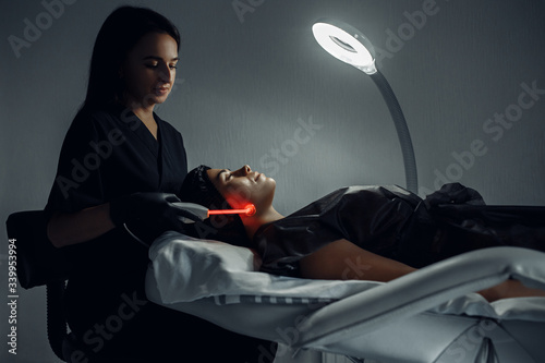 Cosmetologist makes the procedure electrotherapy of the facial skin of a beautiful. photo