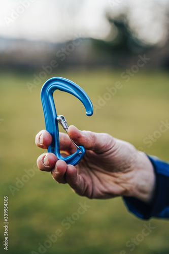 Close up shot of a climbing carabiner in climber's hand. Colorful biner for climbing and mountaineering. Detail shot of climbing equipment. photo