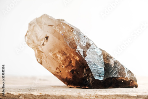 Smoky quartz crystal on a wooden surface on a white background. Copy  empty space for text