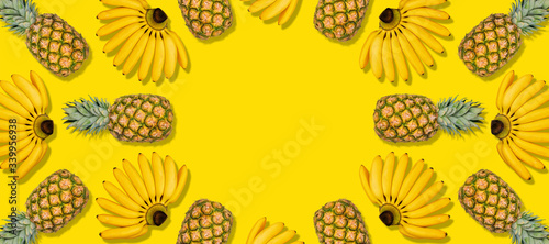 Trendy colorful bananas pineapple pattern on yellow. Tropical abstract fruit summer background. Many tropic fruits. Minimal summer food concept. Flat lay  top view  copy space