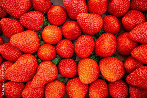 fresh red strawberries lie side by side in a box
