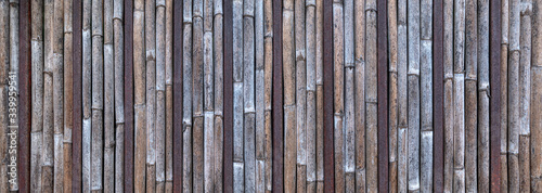 Panorama Wand aus vertikalen verwitterten Bambusrohren und braunen rostigen Metallstangen