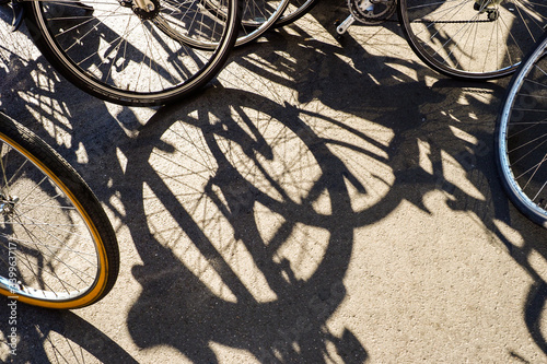 Die in der Stadt geparkten Fahrräder werfen lange Schatten auf den Asphalt.