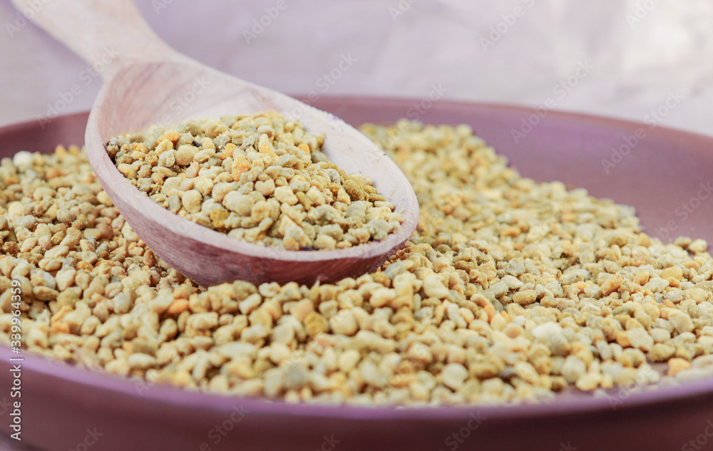 Yellow bee pollen in a brown ceramic plate and in a wooden spoon Yellow bee pollen in a brown ceramic plate and in a wooden spoon
