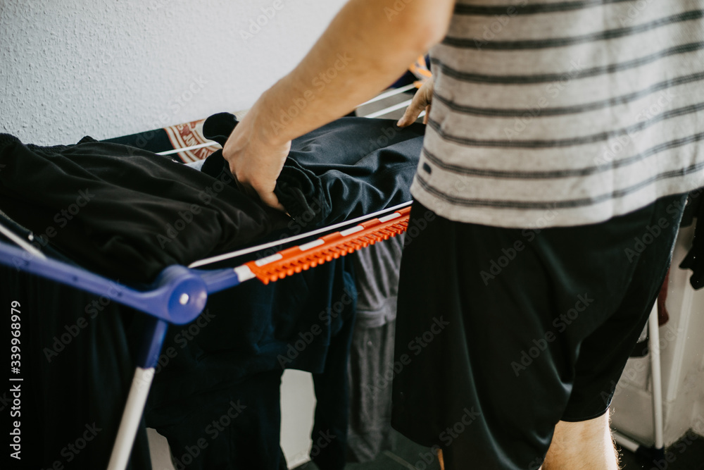 Man doing his laundry at home, washing and folding clothes.