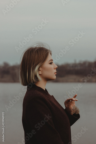 young woman on the beech with flower in the hand with short hair near the lake river blond hair 