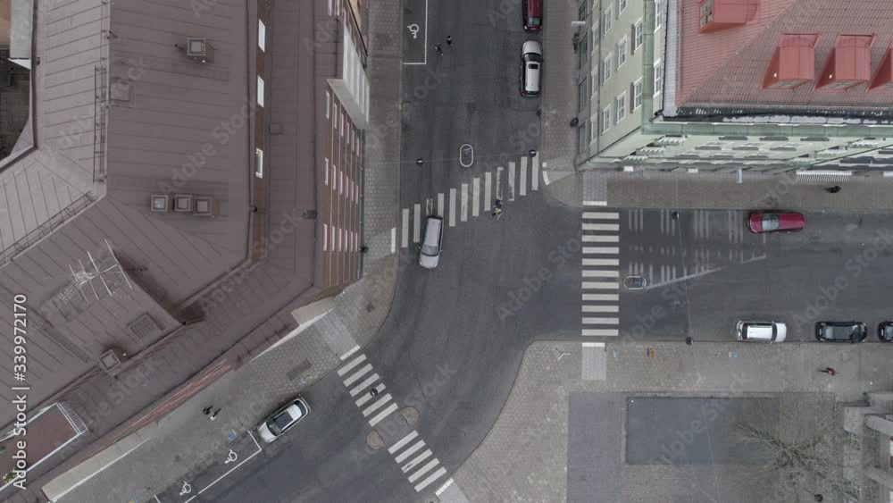 Aerial top down view of city street in Stockholm, Sweden. Grey car driving by. Drone shot flying over intersection, parked cars and buildings Aerial top down view of city street in Stockholm, Sweden. Grey car driving by. Drone shot flying over intersection, parked cars and buildings