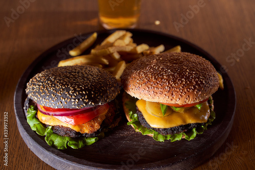 Two burgers dark and light leat on a wooden tray closeup