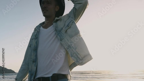 Man in black hat on beach looks on sides, from wind hat falls