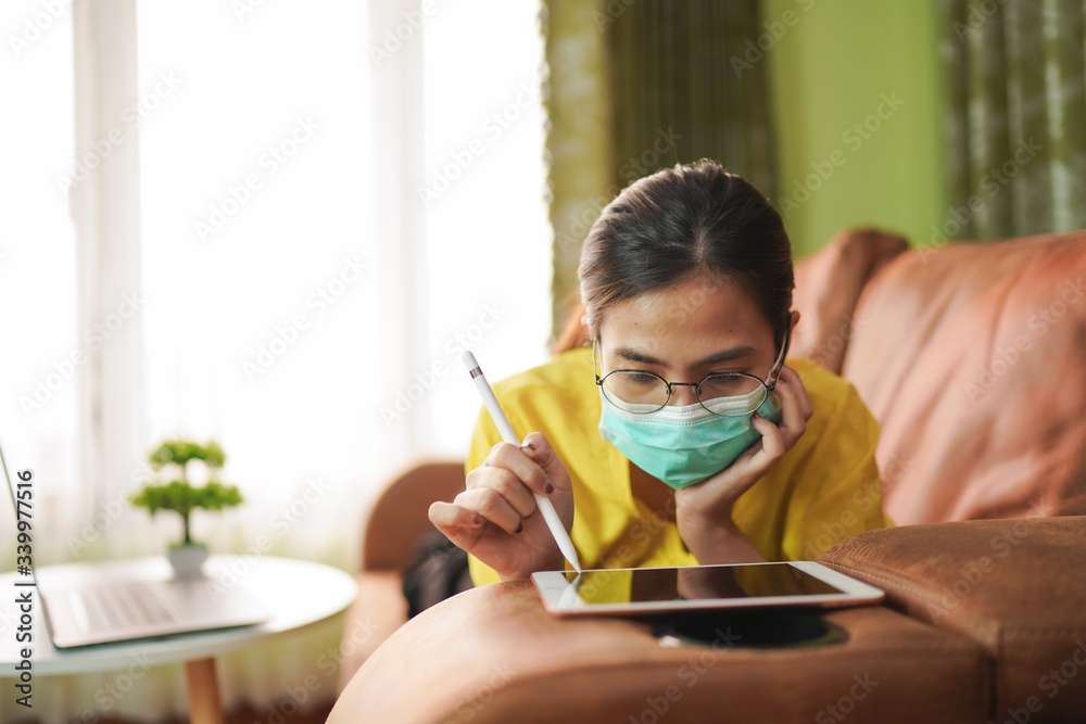 Young asian woman isolating at home with tablet on the sofa in the living room. She is bored because stay at home campaign for coronavirus prevention. Young asian woman isolating at home with tablet on the sofa in the living room. She is bored because stay at home campaign for coronavirus prevention.
