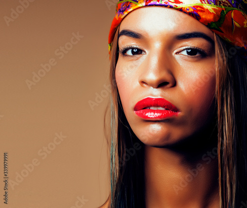 pretty young african american woman with shawl on head posing cheerful on brown background, lifestyle people concept