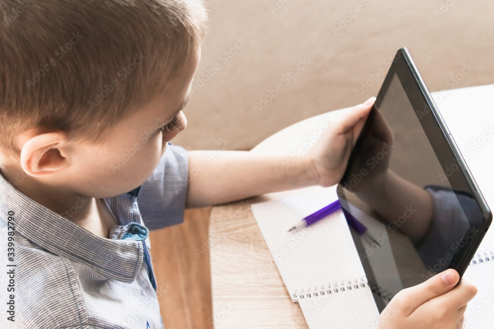 A child is learning distance learning lessons on a tablet. A child is learning distance learning lessons on a tablet.