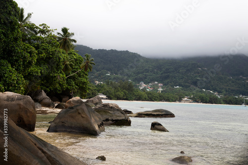 View of a tropical island with large rocks in the ocean, coconut trees by the ocean