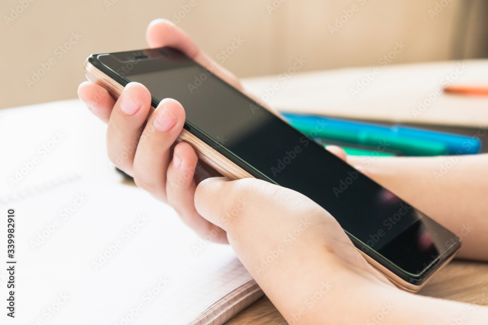 A child is learning distance learning lessons on a mobile phone.
