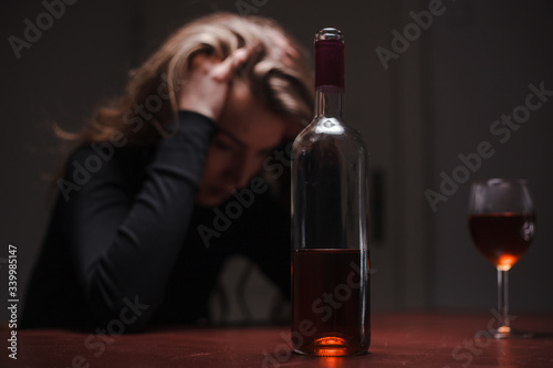 Young beautiful woman in severe depression, drinking alcohol. The concept of abuse and alcoholism. Alcoholic woman with bottle and glass of wine. 