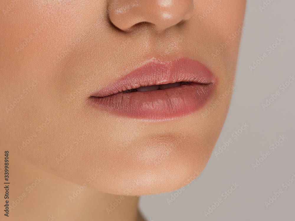 Fototapeta premium Sexual full lips. Natural gloss of lips and woman's skin. The mouth is closed. Increase in lips, cosmetology. Natural lips. Great summer mood with open eyes. fashion jewelry. Pink lip gloss
