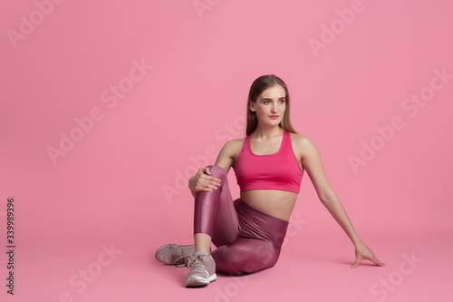 Strong, resting. Beautiful young female athlete practicing in studio, monochrome pink portrait. Sportive fit caucasian model cheerful. Body building, healthy lifestyle, beauty and action concept. © master1305