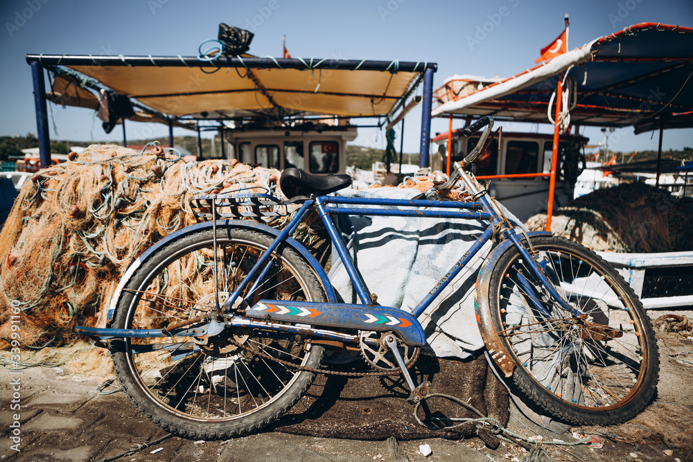 07.07.2018 Istanbul, Turkey: old rusty bicycle stands near a large pile of fishing nets on the pier of a small fishing village 07.07.2018 Istanbul, Turkey: old rusty bicycle stands near a large pile of fishing nets on the pier of a small fishing village