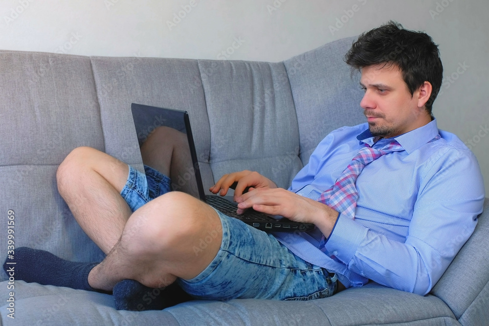 Freelancer Man working typing on laptop at home sitting on couch, freelance distant work on quarantine. Coronavirus pandemic. Self empoyed businessman, COVID-19 epidemic. Wearing Casual Style. Freelancer Man working typing on laptop at home sitting on couch, freelance distant work on quarantine. Coronavirus pandemic. Self empoyed businessman, COVID-19 epidemic. Wearing Casual Style.