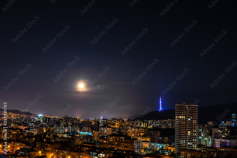 Fototapeta premium Moon rising and stars in night sky over Tbilisi