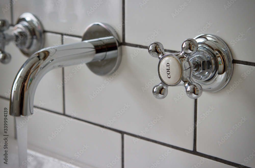 Wall mounted chrome tap/faucet in white tiled bathroom Wall mounted chrome tap/faucet in white tiled bathroom