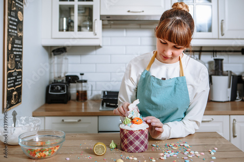 A gloved cook sticks a ginger cookie shaped like an Easter Bunny into the icing of an Easter cake