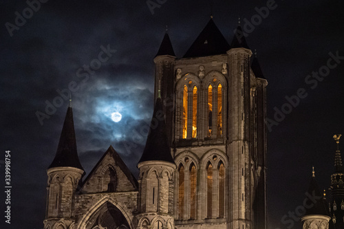 detail of the tower of Saint Nicholas Church, Ghent with the moon