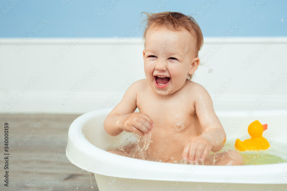 hygiene and care for young children. one year old baby bathes in the bathroom. Portrait of a cheerful laughing girl who bathes in a small bath with soapy foam hygiene and care for young children. one year old baby bathes in the bathroom. Portrait of a cheerful laughing girl who bathes in a small bath with soapy foam