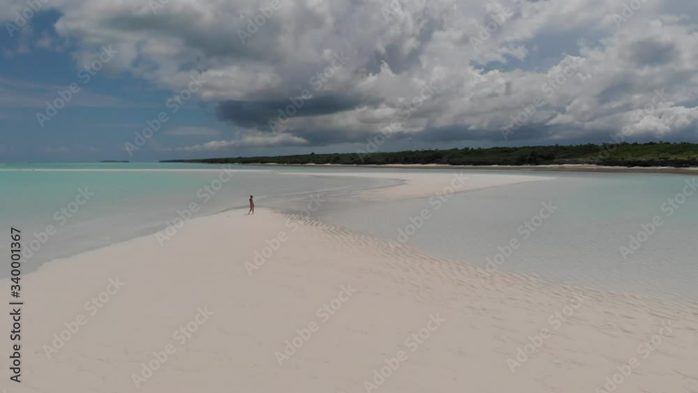 Aerial drone view of a woman walking and running alone on a sandbank near to the clear blue water of Indian Ocean Aerial drone view of a woman walking and running alone on a sandbank near to the clear blue water of Indian Ocean