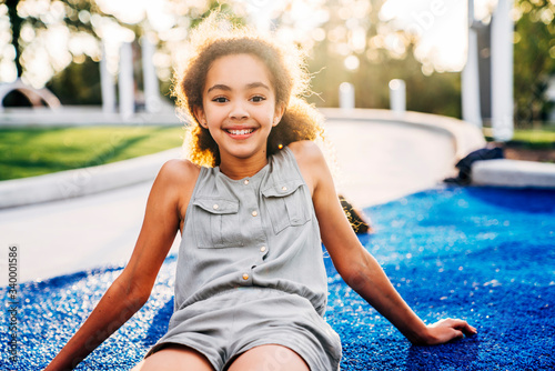 Portrait of smiling tween girl sitting in park at sunset