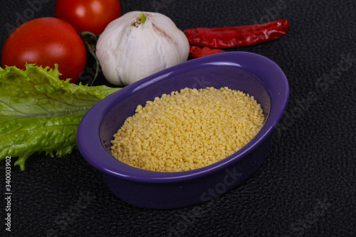 Raw couscous in the bowl served salad leaves, tomato and pepper photo