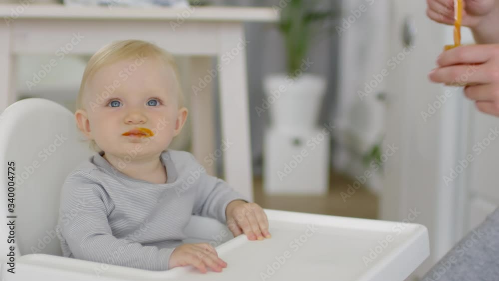 Close up shot of unrecognizable father feeding vegetable puree to adorable toddler girl sitting in highchair Close up shot of unrecognizable father feeding vegetable puree to adorable toddler girl sitting in highchair