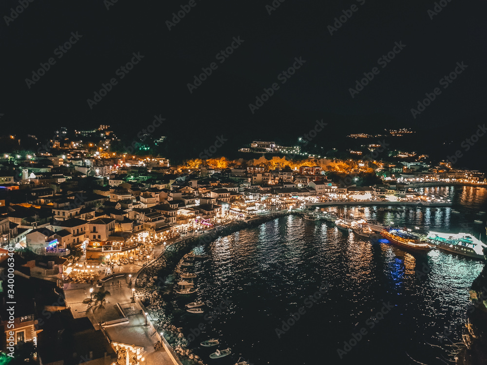 Aerial panoramic cityscape view of Parga city, Greece during the Summer. Beautiful architectural colorful buildings illuminated at night and night traffic near the port of Parga Epirus, Greece, Europe