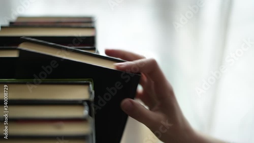 Girl's hand selects a book and takes it from the shelf. Selective focus