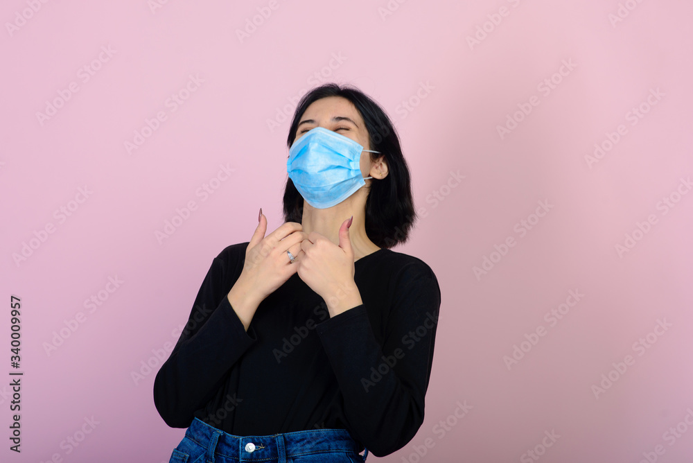 The caucasian girl in blue colored protective face mask. The girl looking at camera. Portrait shot over pink background. virus and pollution protection concept.