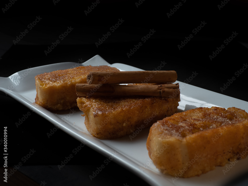 three french toast with cinnamon on white plate and dark background three french toast with cinnamon on white plate and dark background