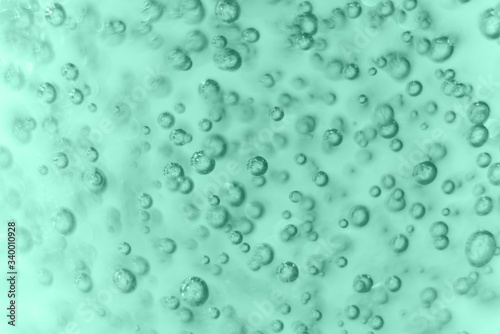 Many round bubbles of the shower gel on the mint background.
