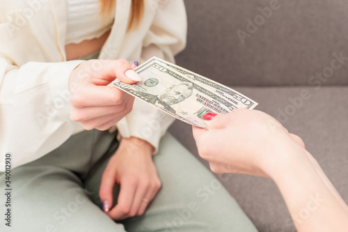 Female hand is giving money to young woman at work, close-up. Business concept.