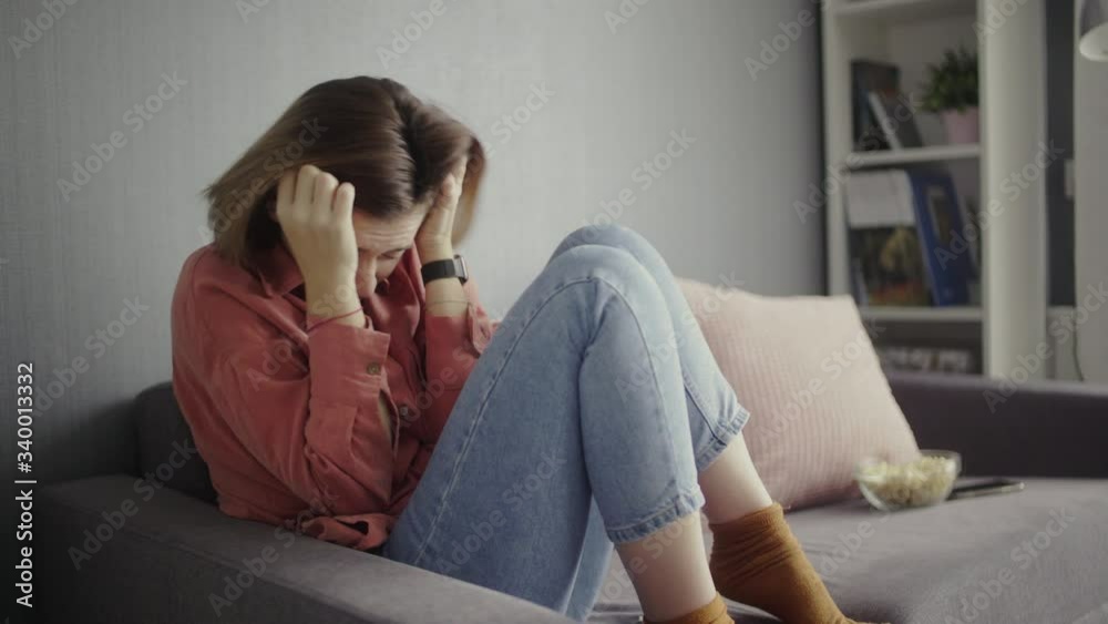 Scared woman sitting on the sofa and watching horror movie Scared woman sitting on the sofa and watching horror movie