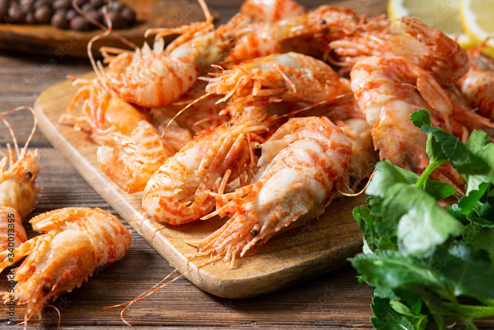 Shrimp on a wooden Board on a brown wooden table. Greenlandic prawns Shrimp on a wooden Board on a brown wooden table. Greenlandic prawns