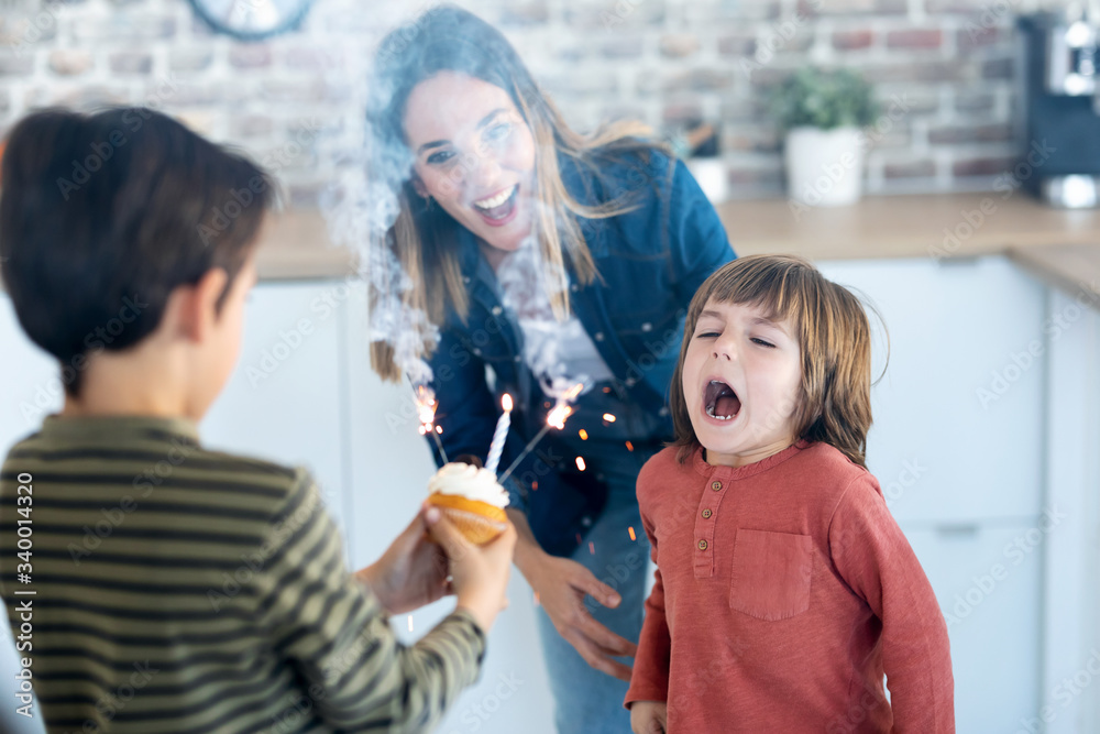 Funny boy blowing out the candles on his birthday cake while his brother is holding it at home. Funny boy blowing out the candles on his birthday cake while his brother is holding it at home.