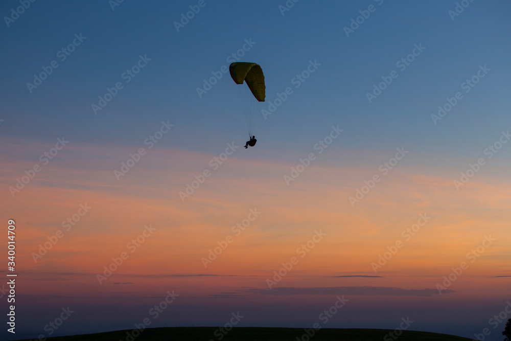 Paragliding silhouette flying at sunset, Brazil