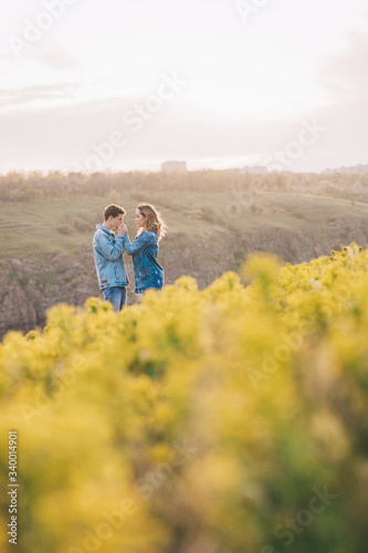 couple in love in blue jeans and white shirts in nature  where the field and rocks