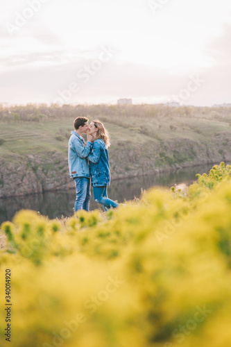 couple in love in blue jeans and white shirts in nature  where the field and rocks
