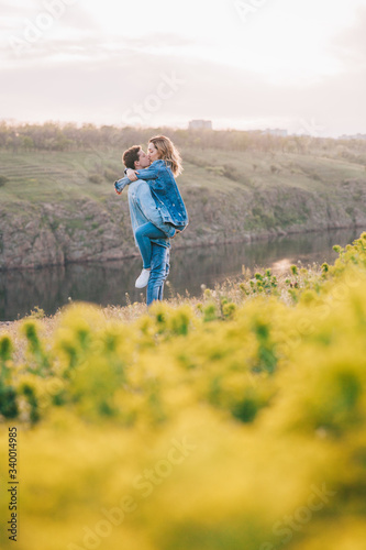 couple in love in blue jeans and white shirts in nature, where the field and rocks © Олег Блохин