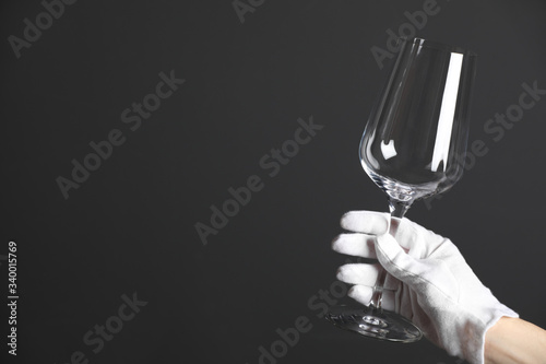 Fotografie Person in white glove checking cleanliness of glass on dark background, closeup